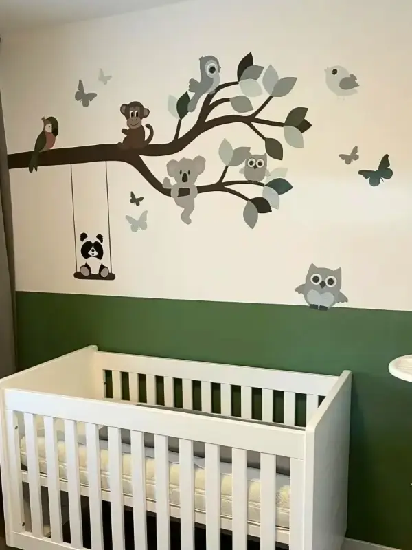 Behangsticker tak met vrolijke dieren in een groene babykamer